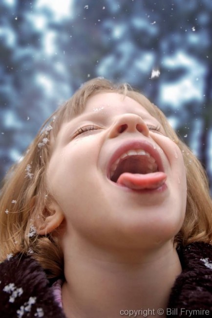 while it is snowing a girls tries to catch a snowflake with her mouth