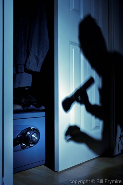 silhouette of a robber inside a house spotting a safe with in a closet