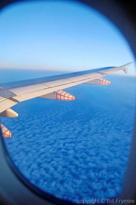 photo of wing taken out airplane window above the clouds