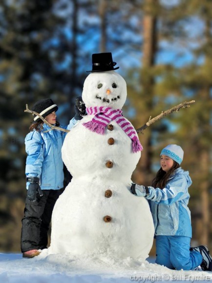 Two girls building snowman - model released