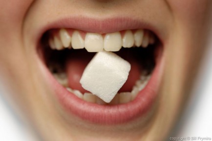 Girl with sugar cube in her teeth