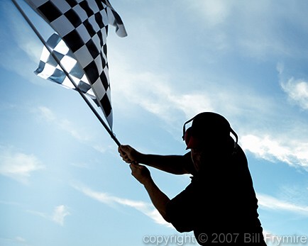man in silhouette waving checkered flag