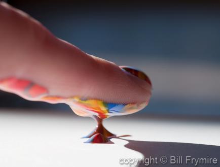 Finger in a blob of colorful paint
