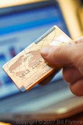 hand holding credit card in front of laptop