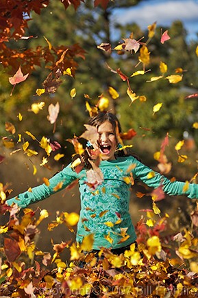 girl playing in leaves