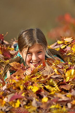 girl playing in a pile of leaves