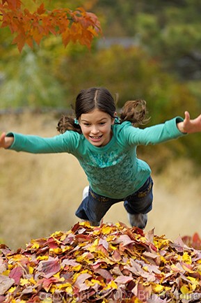 girl jumping in leaves