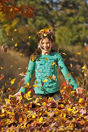 girl playing in leaves