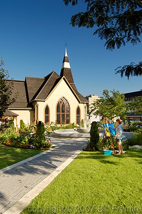 artist painting in a garden by a church