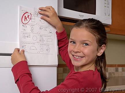 girl putting test on fridge door