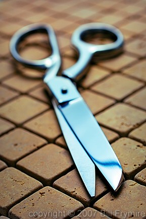 chrome scissors on stone tile background