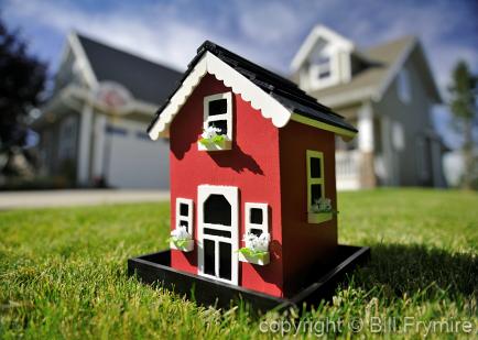 red toy little house infront of real house