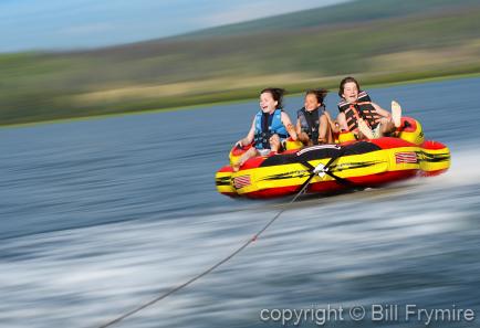 three children tubing on the lake