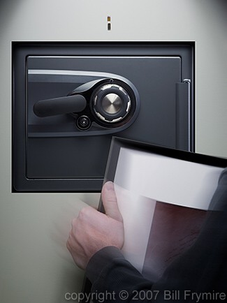 person revealing wall safe behind picture