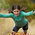 girl jumping in leaves