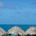 grass palapas on beach with sunny blue skys waters