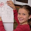 girl putting test on fridge door